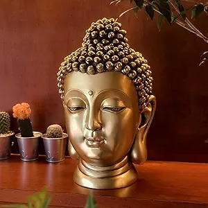 A golden Buddha head statue, with a detailed design, sits on a wooden surface.