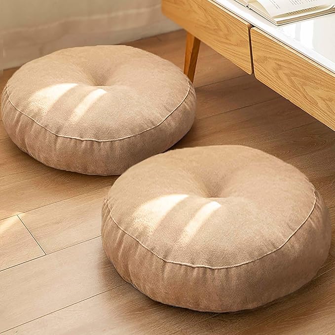 Two light beige round floor cushions on a light brown wooden floor.