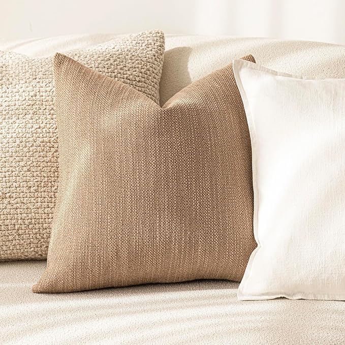 Two light beige throw pillows on a light beige couch.