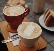 Delicious latte art accompanied by a slice of cake on a cafe table.